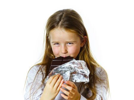 Cute little girl eating tablet of chocolate, isolated on white backgroundの写真素材