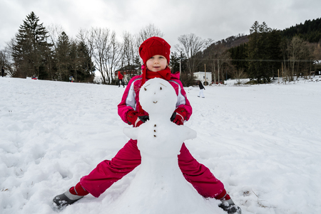 Little girl making snowman winter day, januaryの写真素材