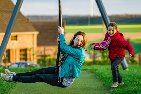 Two sisters: preschooler and teenage - playing on playground, sunny eveningの写真素材