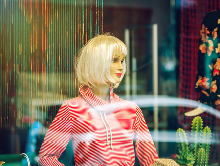 Woman mannequin inside the shop, view through the window with reflectionsの写真素材