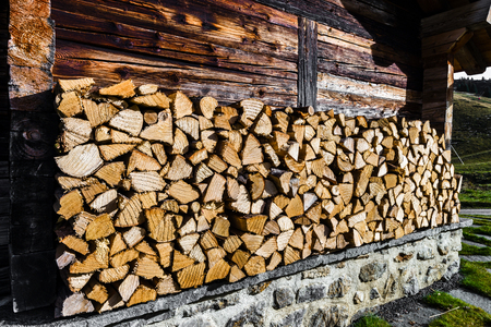 The stack of firewoods near the wall of old-styled wooden hut, Alps