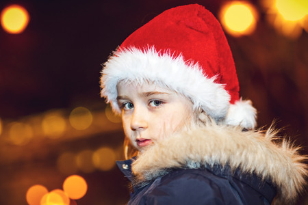 Cute little girl in red hat posing on the street with bokeh light, christmas time, Strasbourgの写真素材