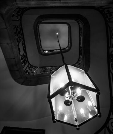 Ancient spiral staircase in old house with big lamp connected on long metal chain, Franceの写真素材