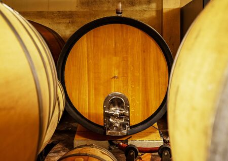 Oak barrels of wine in the basement of an Italian winemaker. Old wine production technology. Italy.の写真素材