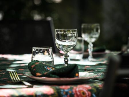 A simple but elegant tablecloth and cutlery laid out on it. Crystal glasses in the sun. Everything is ready for lunch in the garden.France.の写真素材