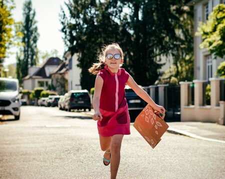 Emotional photos of a schoolgirl girl who runs along the street in the bright sun. Franceの写真素材