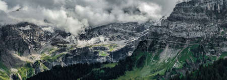 Terrible lifeless rocks, a glacier in the Alps, clouds and fog spread over the peaks of the...