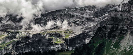 Terrible lifeless rocks, a glacier in the Alps, clouds and fog spread over the peaks of the...