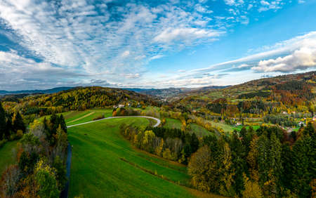 A drone rises above a multi-colored valley in the Vosges. Yellow, orange, red tree crowns. Multicolored autumn vineyards. Sunlit hills.の写真素材