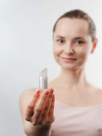 Beautiful Young Woman with Clean Fresh Skin showing the product for skin care. Girl beauty face...