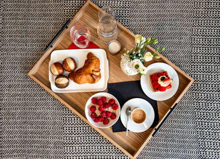 Breakfast in bed. Raspberries, coffee, cake, croissant. Cozy hotel. Tourism and travel.の写真素材