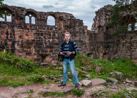 A man controls a drone and photographs himself, standing in the middle of the mountains on the ruins of a medieval castle. Franceの写真素材