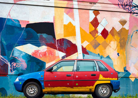 A painted old car against the background of a multi-colored wall. Street art.の写真素材