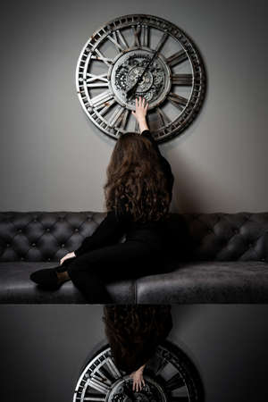 Girl and time. Beautiful young girl posing against the background of a wall clock.の写真素材