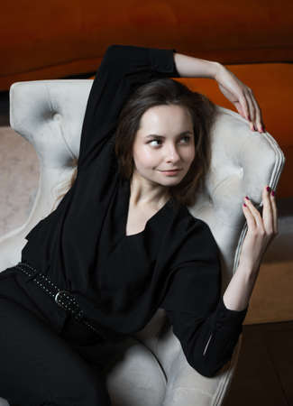 Beautiful young girl posing in a chic white armchair.