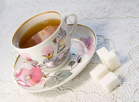 cup of tea and white lump sugar on a light tableclothの写真素材