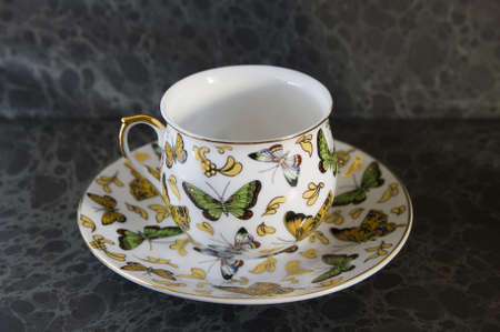 butterfly on antique teacup on a dark backgroundの写真素材