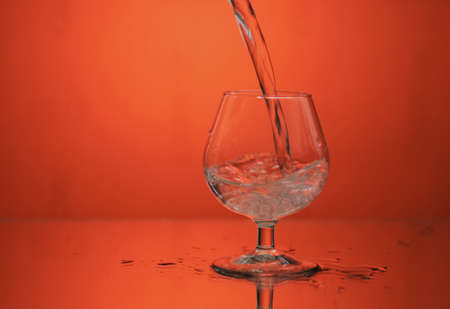 glass on a mirror and reflection orange backgroundの写真素材