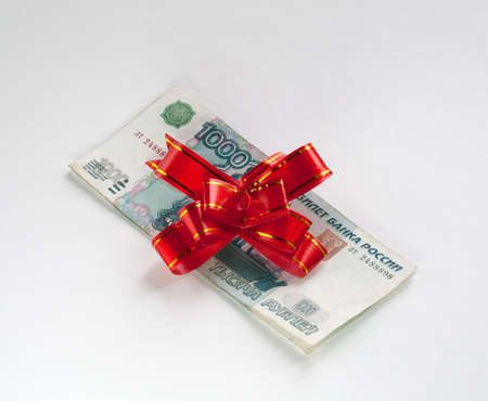 Money and red gift bow on light backgroundの写真素材