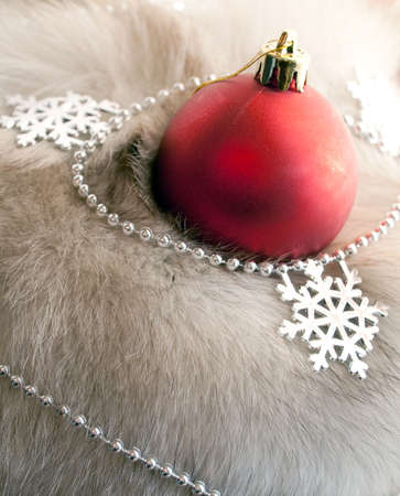 A red Christmas ball and snowflakes on a white furry backgroundの写真素材