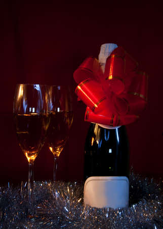 Two glasses of champagne and bottle over dark red backgroundの写真素材