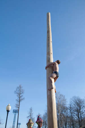 PENZA, RUSSIA - February 14. Celebration of Shrovetide (Maslenitsa) in russian cityman try to climb up a column (russian entertainment)のeditorial素材