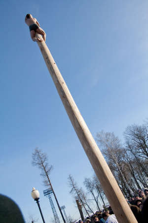 PENZA, RUSSIA - February 14. Celebration of Shrovetide (Maslenitsa) in russian cityman try to climb up a column (russian entertainment)のeditorial素材