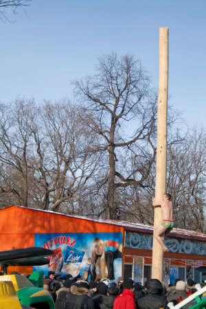 PENZA, RUSSIA - February 14. Celebration of Shrovetide (Maslenitsa) in russian cityman try to climb up a column (russian entertainment)のeditorial素材