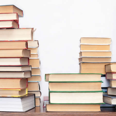 pile of old books on a wooden table on light backgroundの写真素材