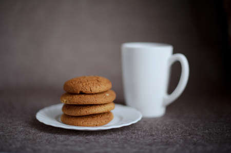 Oatmeal cookies on a white plate and tea on brown backgroundの写真素材
