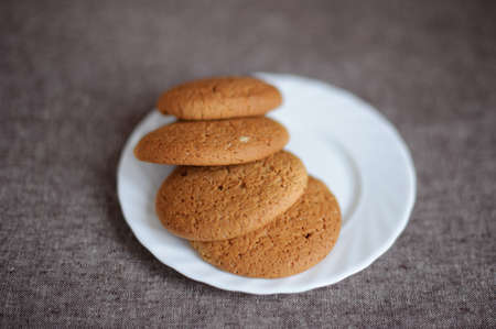 Oatmeal cookies on a white plate on brown backgroundの写真素材