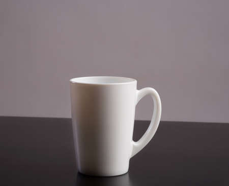Empty White cup standing on dark table
