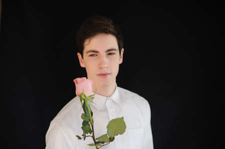 young man with a rose on the black backgroundの写真素材