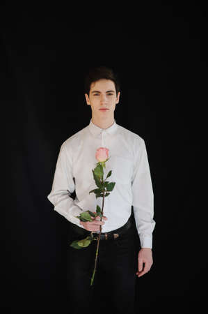 young man with a rose on the black backgroundの写真素材