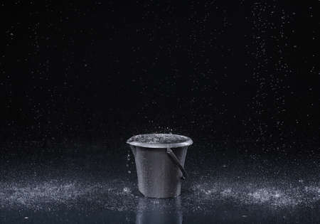 Bucket with water drops on dark backgroundの写真素材