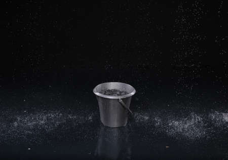 Bucket with water drops on dark backgroundの写真素材