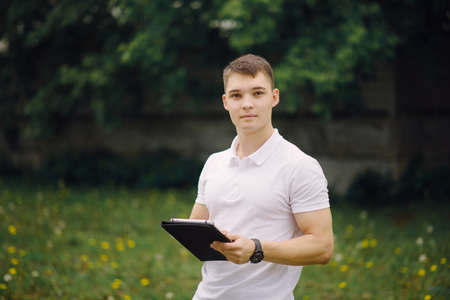 Portrait of standing young man with tablet pc outdoors. Serious young mam using digital tablet pc.の写真素材
