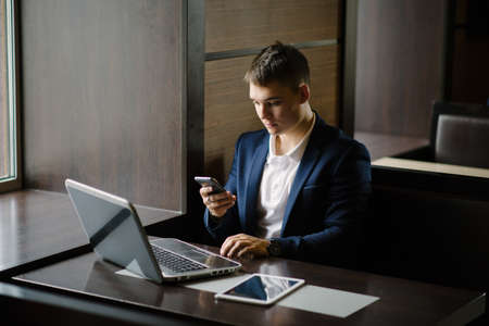 Portrait of a young businessman seeing on his smartphone in cafe.