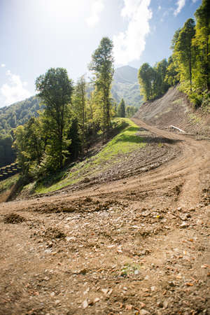 Turn on Dirt Road and Forest Landscape on Krasnaya Polyana. Sochi. Russia. Hills with Evergreen Trees. Summer Mountain Landscape.の写真素材