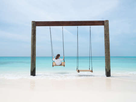 Young Woman on Swing in Indian Ocean on Tropical Maldivian Beach. Bright Summer Concept.の写真素材