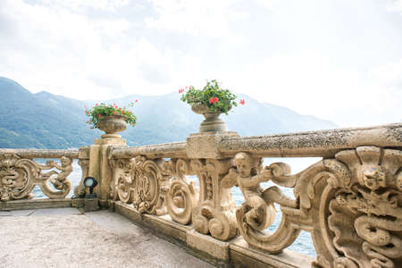 Villa Balbianello. Lake Como. Italy - July 19, 2019: Old Classic Balustrade with Flowers Pot on Villa Balbianello. Lake Como. Italy. Ancient Fence. Ancient Architecture Baroque.のeditorial素材