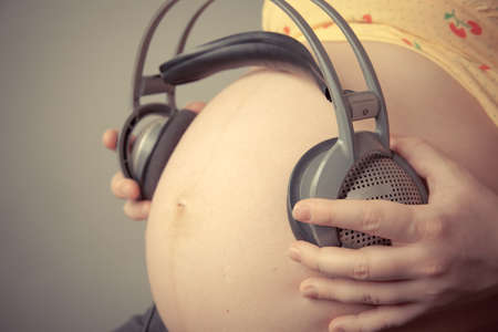 Pregnant woman s belly  Unborn child listens to music with headphones の写真素材