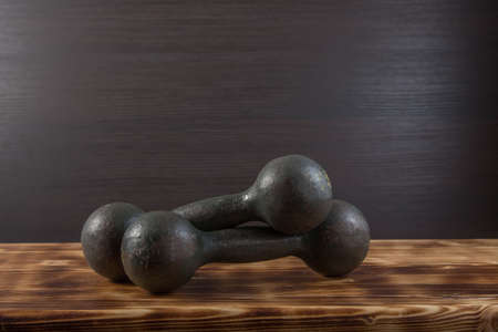 Old dumbbells on wood surface. Dark background.の写真素材