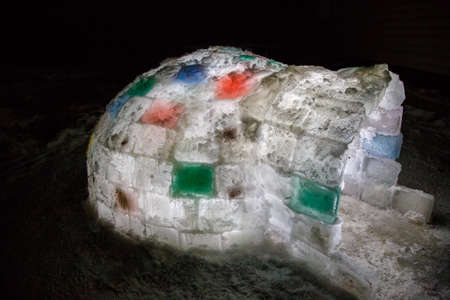 Random color igloo, illuminated from the inside on a dark background.