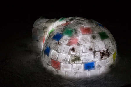 Random color igloo, illuminated from the inside on a dark background.の写真素材