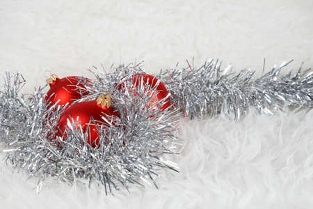 Red christmas ball with silver tinsel on a white furの写真素材