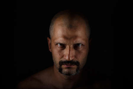 Brutal man with a short haircut, a mustache and a beard on a dark backgroundの写真素材