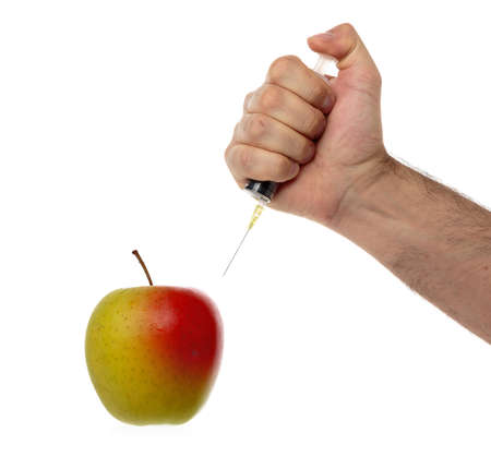 Male hand makes an injection syringe into an apple isolated on white.の写真素材