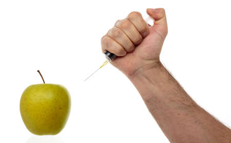 Male hand makes an injection syringe into an apple isolated on white.の写真素材