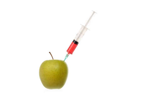 Syringe with colored liquid stuck into an apple isolated on white.の写真素材